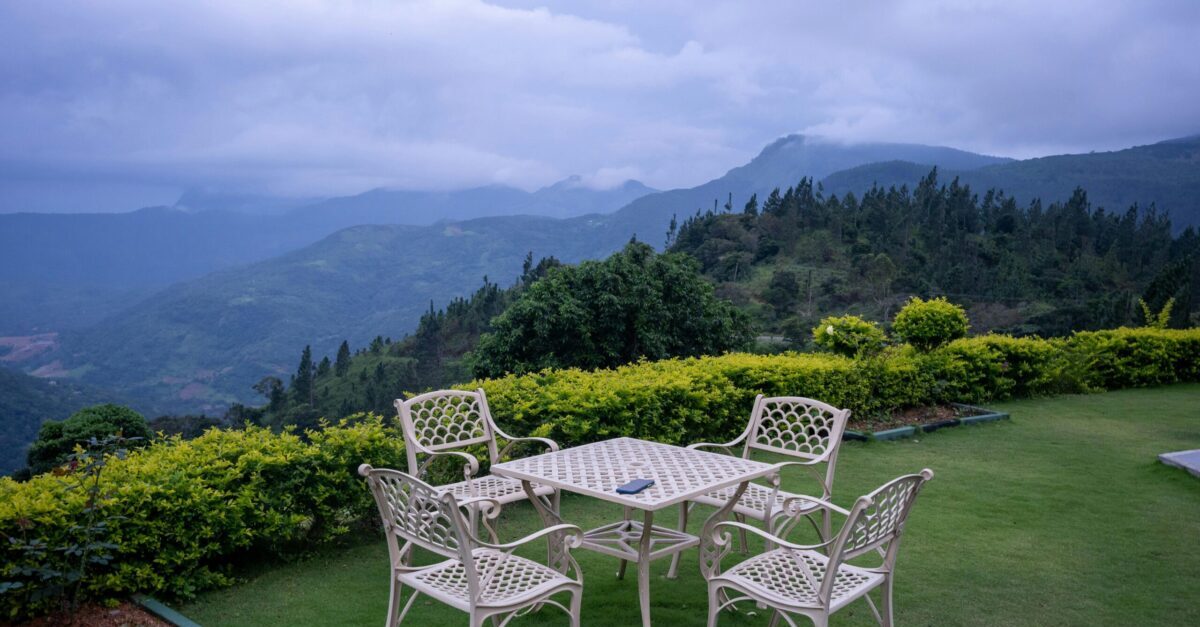 Outdoor patio set overlooking lush mountains under a cloudy sky.