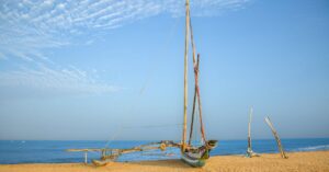 Rustic fishing boats resting on Negombo Beach against a clear blue sky, Sri Lanka's scenic coast.