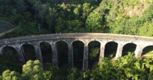 Stunning aerial view of Nine Arches Bridge amidst lush green forest in Sri Lanka.