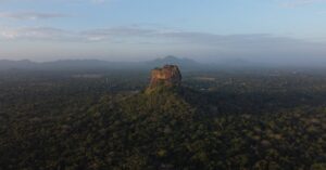 Stunning aerial view of Sigiriya Rock Fortress surrounded by lush forest in Sri Lanka at dawn.