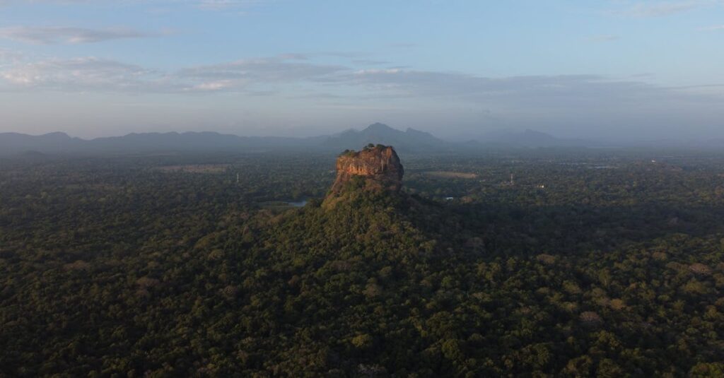 Stunning aerial view of Sigiriya Rock Fortress surrounded by lush forest in Sri Lanka at dawn.
