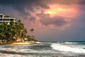Stunning sunset at Unawatuna Beach, Sri Lanka, with palm trees and ocean waves.