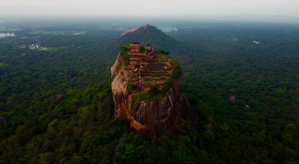 Sri Lanka Travel Guide for First-Time Visitors | Wildlife & Heritage A stunning aerial view of Sigiriya Rock Fortress rising above lush greenery in Sri Lanka.