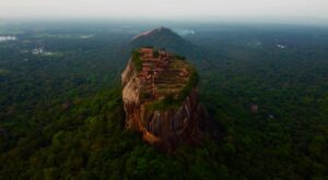A stunning aerial view of Sigiriya Rock Fortress rising above lush greenery in Sri Lanka.
